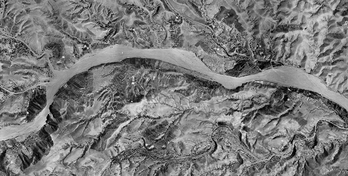 Muestra la morfología sinuosa y textura clara de un cauce natural (riesgo)
